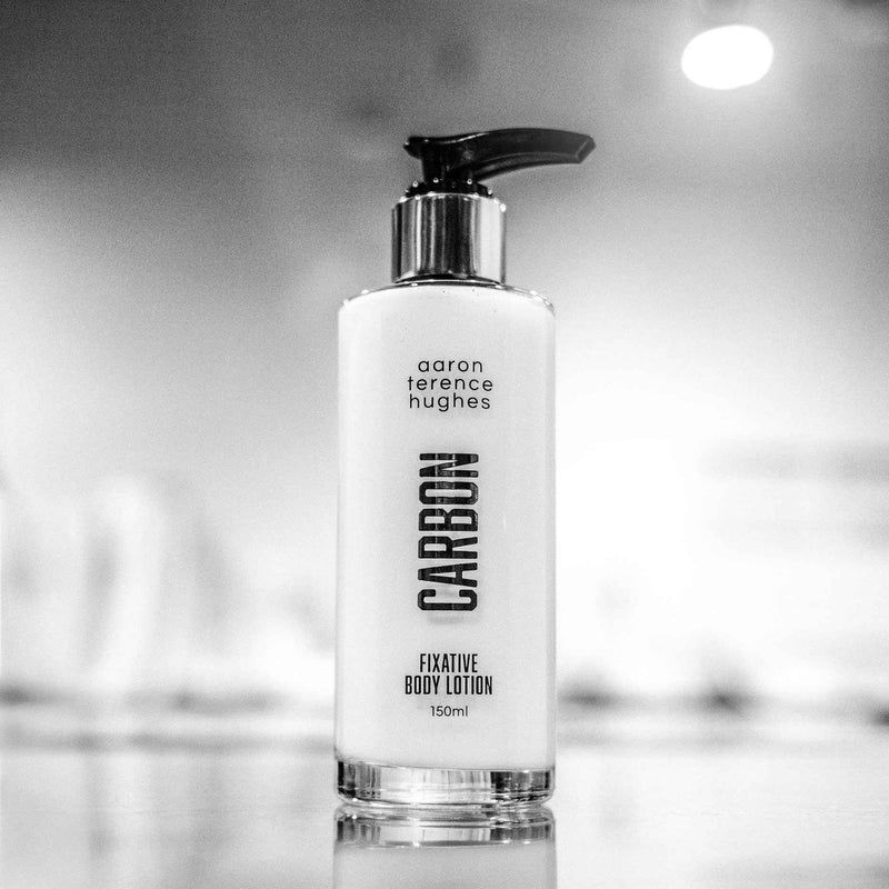 Lotion corporelle fixatrice au charbon de la marque Aaron Terence Hughes, bouteille avec étiquette blanche et logo noir.