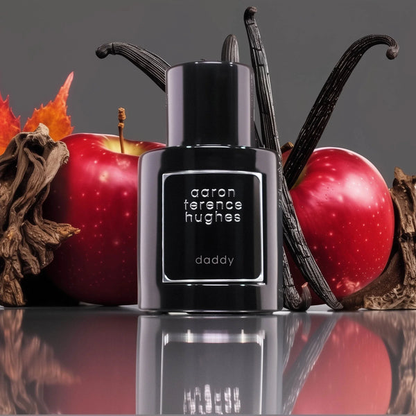 Flacon noir du parfum Aaron Terence Hughes Daddy avec pommes rouges, gousses de vanille et feuilles d'automne.
